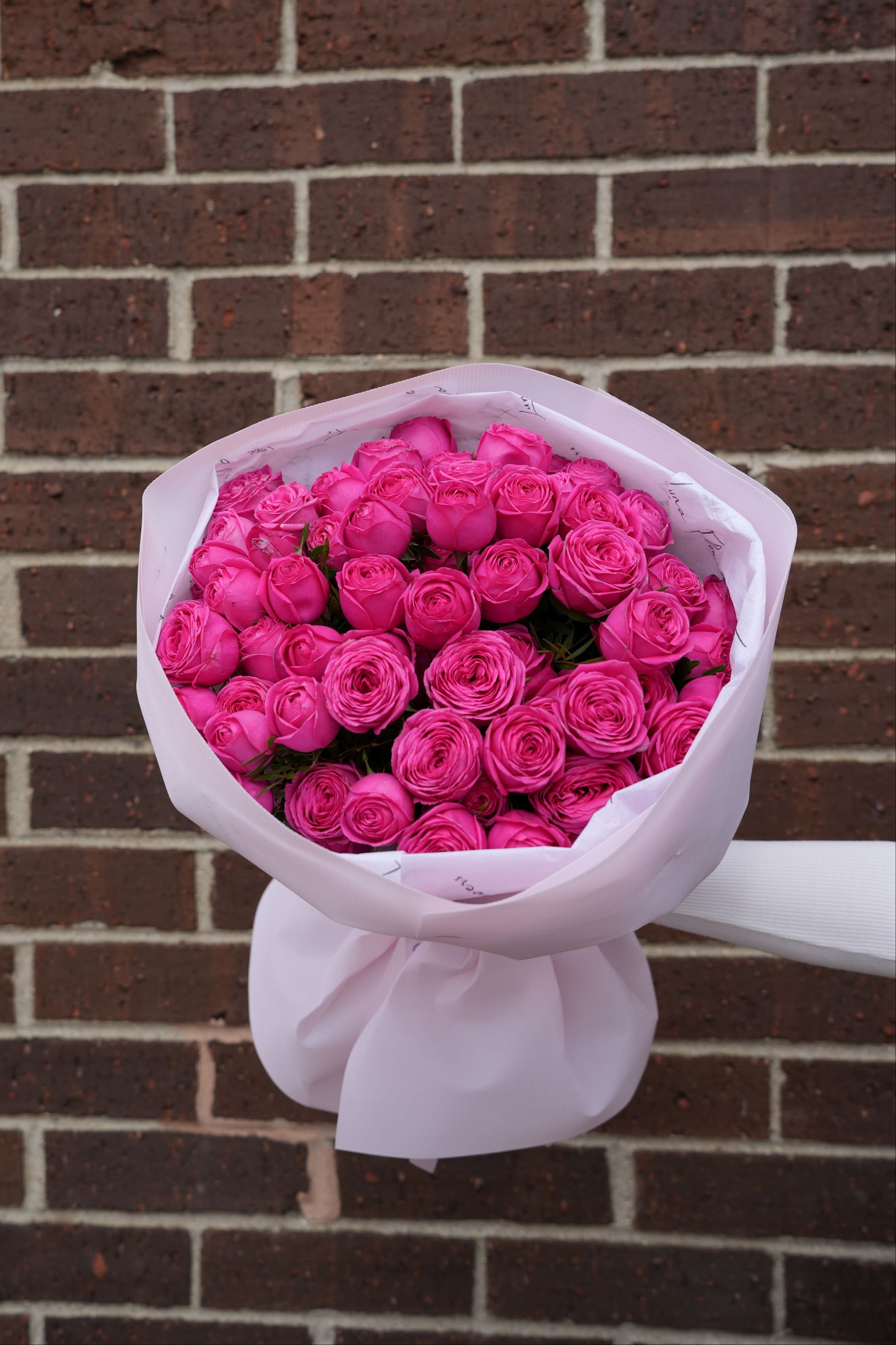 Bouquet of pink roses wrapped in white paper 